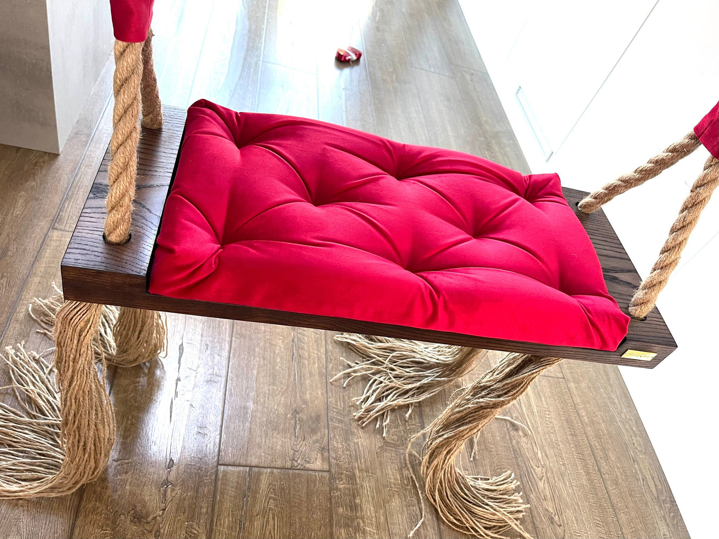 dark oak wooden swing chair with red quilted cushion